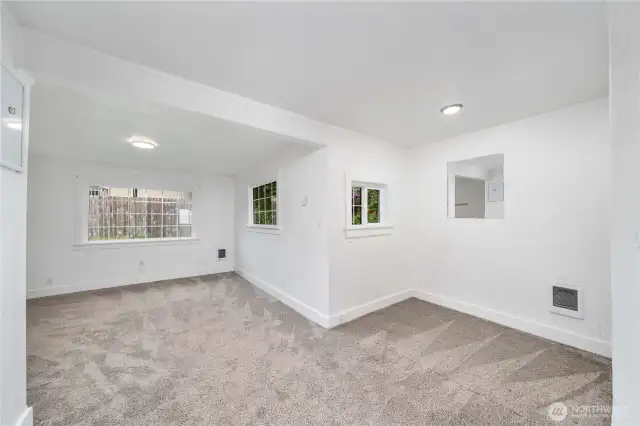 This inviting living room offers a wall of windows that fills the space with natural light. The cozy nook off to the side makes a perfect spot for a small dining table, workstation, or creative corner. Fresh carpet and crisp white walls make it easy to envision your own personal touches in this functional layout.