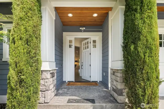 Step inside through a charming covered entry framed by stone columns and crisp white millwork—where timeless curb appeal meets a warm, welcoming interior.