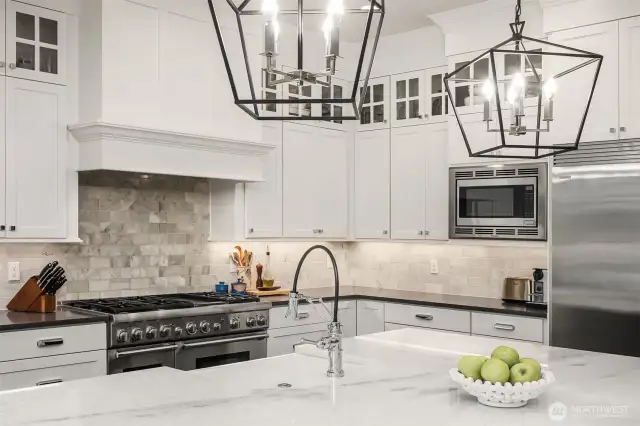 Proof that you can have it all—this gourmet kitchen blends form and function with a powerful pro-grade range, striking stone tile backsplash and statement lighting that’s equal parts drama and design.