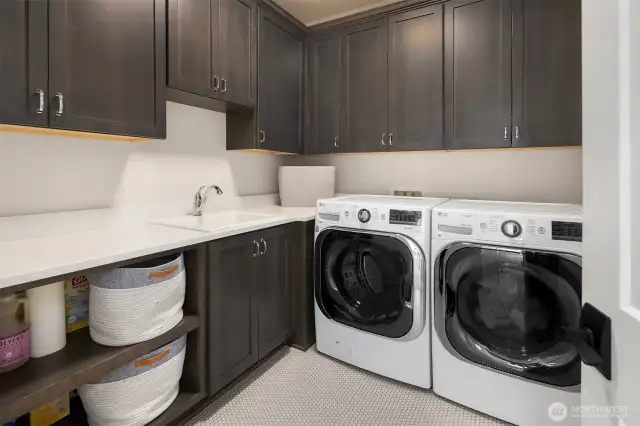 Plenty of elbow room for laundry day—this spacious utility room features extensive cabinetry, deep counters for folding, a soaking sink, and side-by-side LG washer and dryer. Thoughtfully designed to keep household chaos under control.