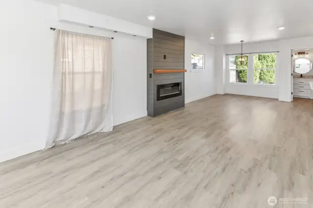 Living room and dining room with a peak of the main level bathroom and electric insert