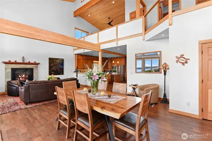 Another view of the dining area with the natural beams, soaring ceilings, and the kitchen beyond. Light filled space with room for a reading nook.