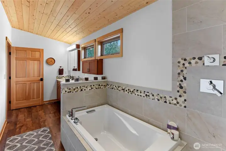 Upstairs primary bath with deep tub and beautiful tile surround.
