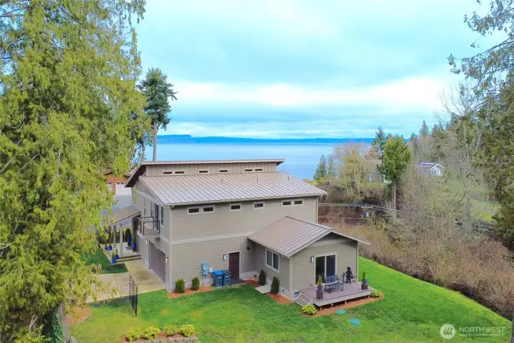 View of the rear of the home. Grass area behind the hiome runs to the tree line.