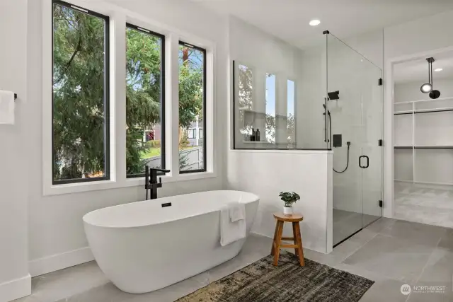 Indulge in luxury with this open, freestanding tub, perfectly positioned against a frameless, curbless fully tiled shower featuring a beautiful tile niche for the ultimate spa experience!