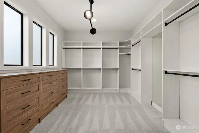 Step into luxury with this stunning primary closet, featuring a custom closet system, built-in dresser, soft carpeting, designer lighting, and a standing mirror—creating a refined space for both style and function!