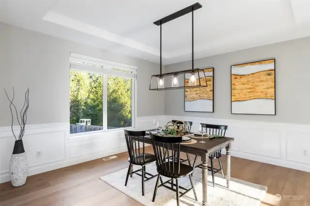 Dining room with updated chandelier, wainscoting, & coffered ceiling.