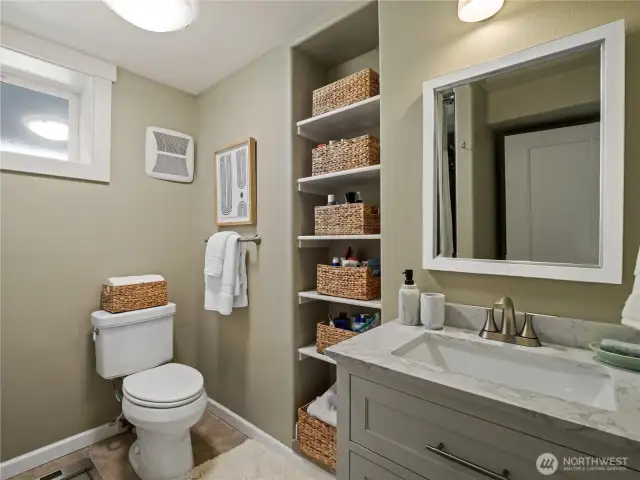 This thoughtfully designed bathroom maximizes space with smart storage solutions and a fresh, neutral aesthetic.