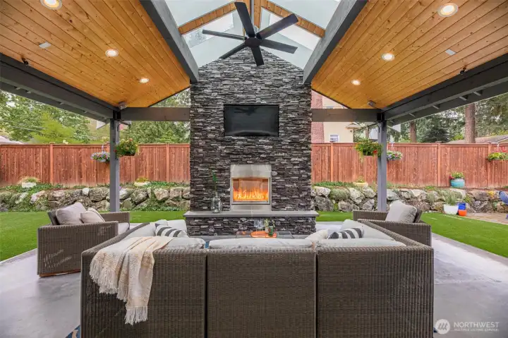 Outdoor Living... This impeccably designed outdoor living space seamlessly blends luxury and function, making it an ideal retreat for Pacific Northwest living. A magnificent covered patio allows for year-round comfort, enhanced by skylights that bathe the space in natural light. The gas-powered stone fireplace serves as a striking focal point, offering warmth and ambiance for elegant gatherings or intimate evenings.