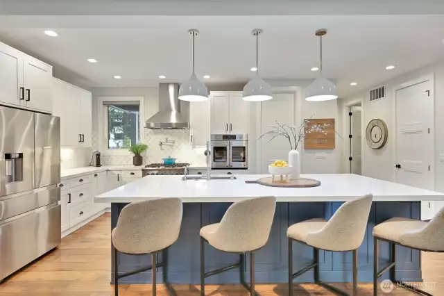 Bathed in natural light, this expansive gourmet kitchen is a showpiece of elegance and functionality. An oversized heated quartz island serves as the centerpiece, offering both warmth and practicality—perfect for casual gatherings or hosting memorable meals. High-end finishes include a custom tile backsplash, high-end appliances, a gas oven, and a built-in French door convection oven for precise culinary excellence. A walk-in pantry, two separate sinks, and abundant storage ensure seamless efficiency, while a pot filler above the range adds effortless convenience. Designed for social connection and sophistication, this space flows openly into the family room, dining room, and covered outdoor living area.