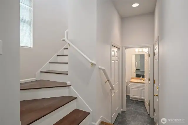 Stairs leading from the entry on the lower level up to the main level rooms - full bath at the end of the hall, garage at right