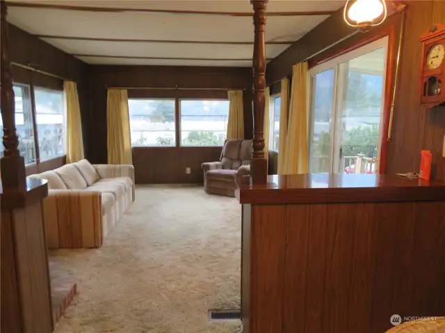 View from the kitchen.  Windows forward and on the sides and the slider out to the deck on the right. New flooring and paint on the paneling would make a world of difference.  New window treatments also.