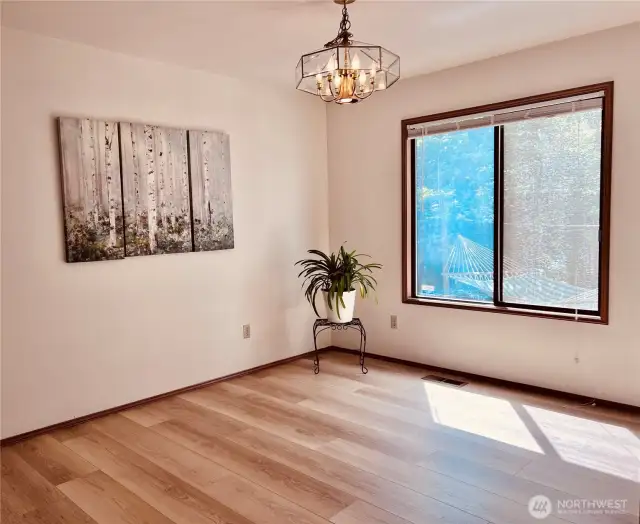 Dining room with large window looking into backyard. New lighting & engineered wood flooring.
