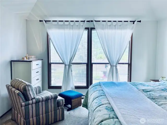 Master bedroom with large windows looking east and street