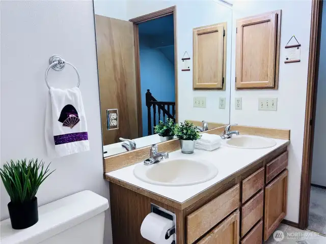 Full bath with access from hallway features double sinks, shower and bathtub. Built-in wall cabinet for storage.
