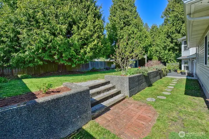 Tiered backyard with fire pit, and garden shed.