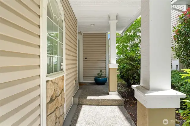 A charming covered walkway framed by mature landscaping offers a quiet, sheltered approach to the front door.
