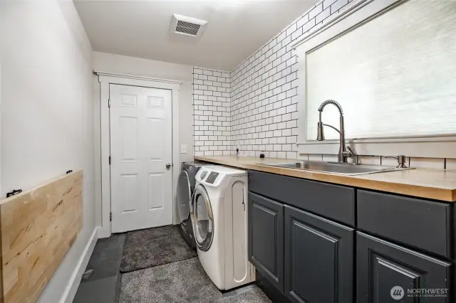 Laundry room with sink, extra storage and includes washer and dryer.