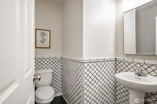 Downstairs half bath also finished in white tiles with black color.