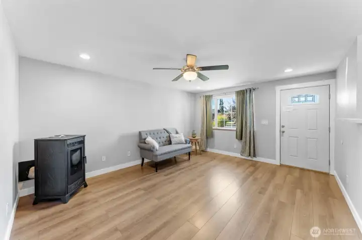 Living room features large window providing an abundance of natural light, beautiful laminate floors, ceiling fan, and pellet stove.