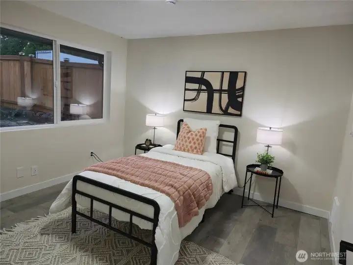 First bedroom just off the hallway to the right — cozy and inviting, with a large window bringing in natural light and soft, modern décor that creates a calm, restful atmosphere.