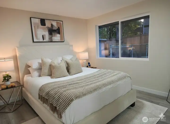 Main bedroom located at the end of the hallway on the left side — bright and comfortable, with a large window facing the fenced backyard and plenty of natural light enhancing the room’s open, restful feel.