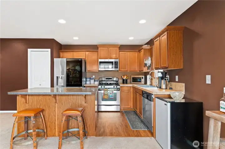 Functional kitchen with stainless appliances, gas range, ample cabinetry, large island, and new luxury vinyl plank flooring.