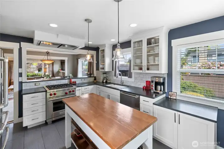 Tressle table in the kitchen is not stationary but stays with the new homeowner. Designer kitchen with abundant storage, stainless appliances, butcher block island, and bright sunlit windows.