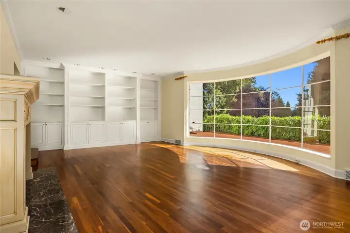 The home is currently vacant, and this is the ivinng room.  Big bay window floods this room with sunshine. Built-in bookshelves and a wood burning fireplace.