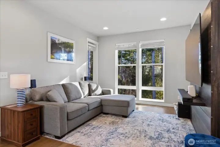 Living area has large windows facing greenbelt & balcony access.