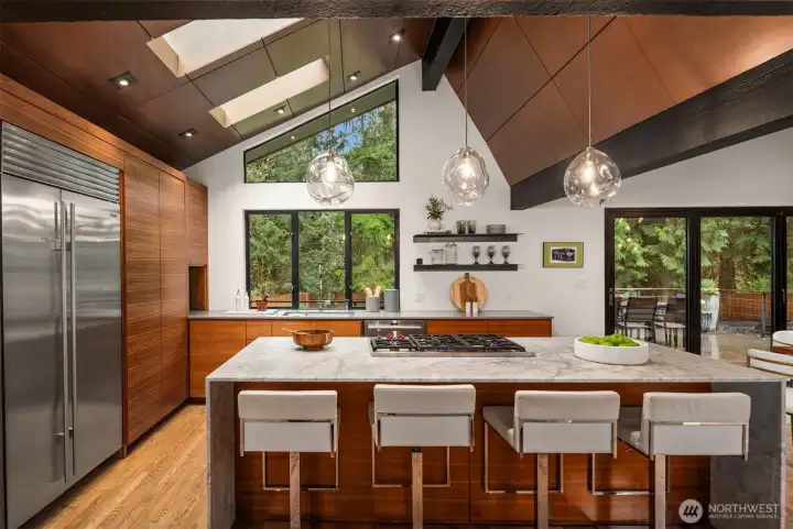Chefs kitchen with marble waterfall island and hand-blown glass pendant lighting by John Pomp