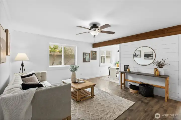This bright and open living area showcases shiplap accent walls, LVP flooring & wood ceiling beam, creating that "farmhouse feel".