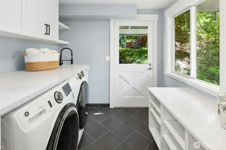 The laundry room doubles as a mud room with built-in shoe shelves and storage cupboards.