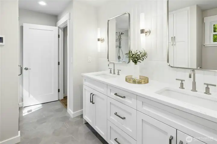 The lower level bathroom has new cabinets, a dual sink vanity, tiled shower, and heated tile floors.