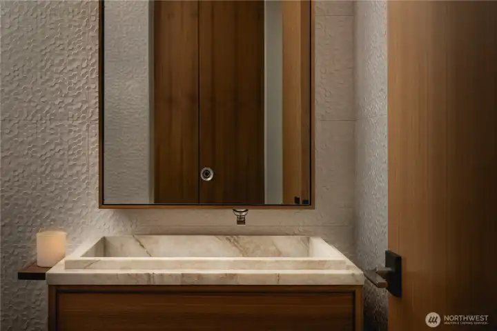 The main level powder room carries the home’s restrained material palette with consistency.
