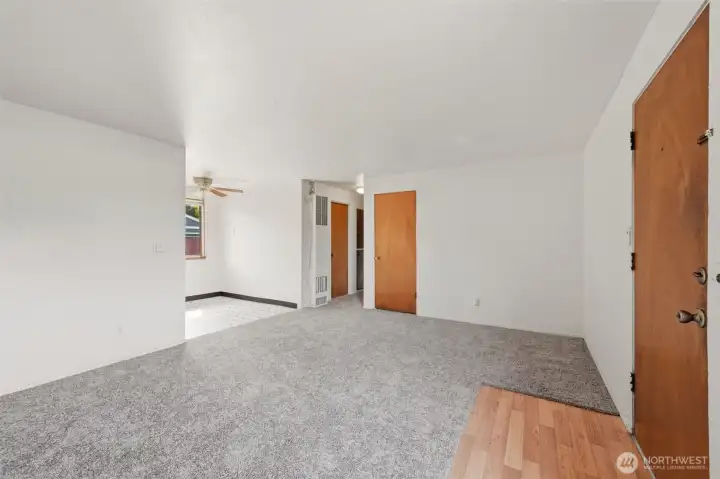 This view of the apartment living room looks towards the dining area and hallway to bedrooms.