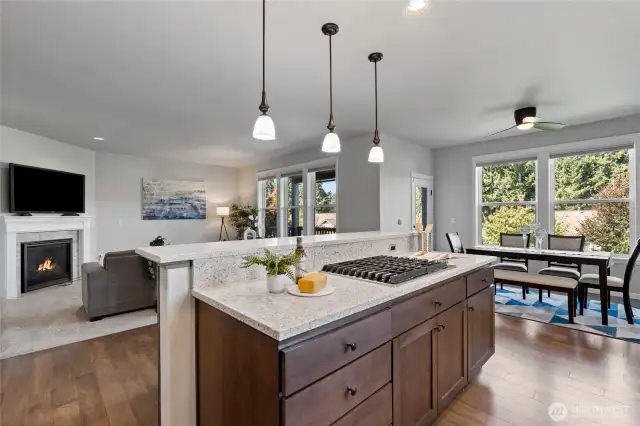 The kitchen island with cooktop, lots of storage and breakfast bar. The door near the table leads to the deck and backyard.