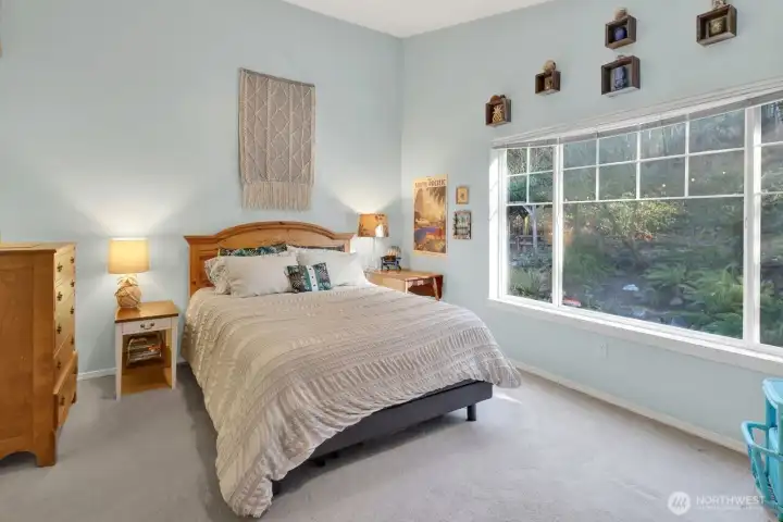 Large window in primary bedroom overlooking private backyard.