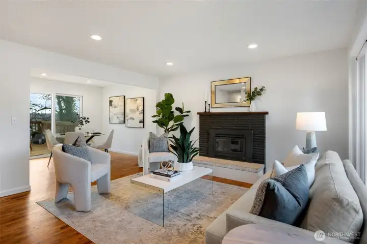 The inviting living and dining room features a cozy fireplace with wood-burning insert