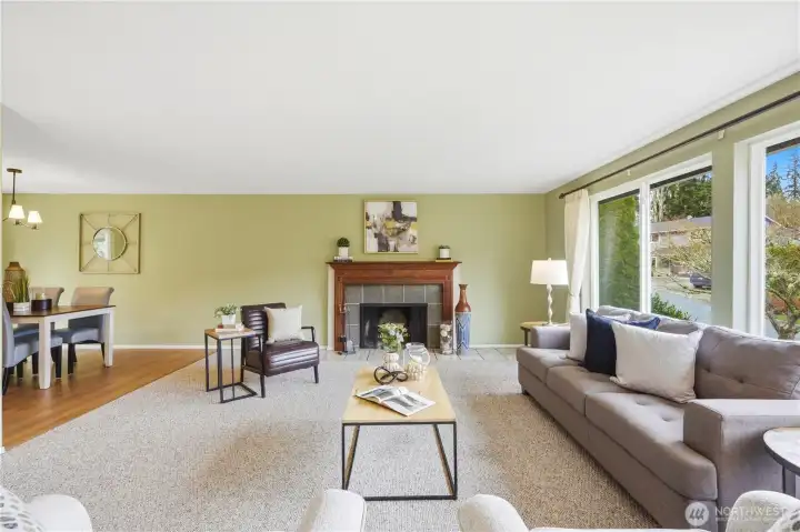 The living room features a wood burning fireplace and large windows that bring in a lot of light. Dining room visible to the left.