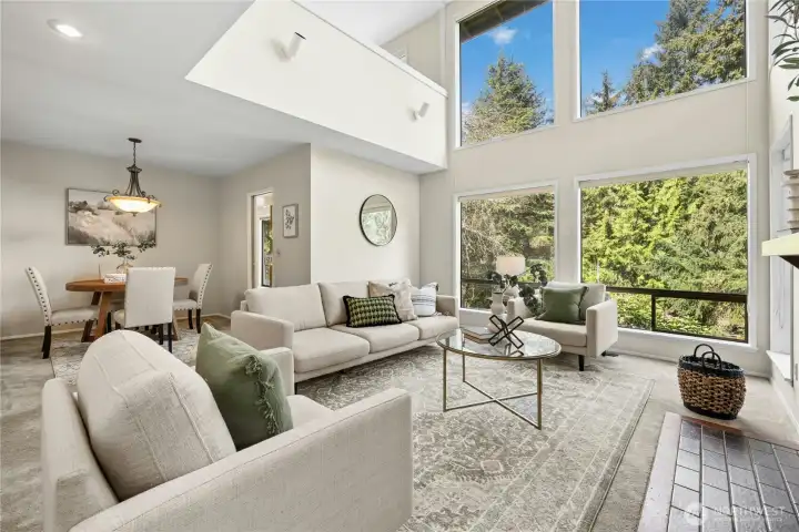 The gracious living room has soaring ceilings and floor to ceiling west-facing windows.