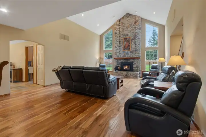 Spacious living aka Great Room with Acacia wood floors, floor-to-ceiling river rock fireplace with wood insert. Vaulted ceilings.