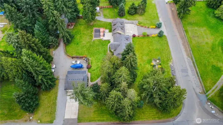 Detached garage on left, gravel driveway on the property accessed by two double gates, main house center, spacious 2.31 Acre corner lot