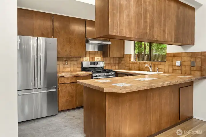Kitchen with updated appliances; Fisher Paykel refrigerator and 5-burner Samsumg gas stove. Convenient kitchen counter for casual dining or chatting with the chef.