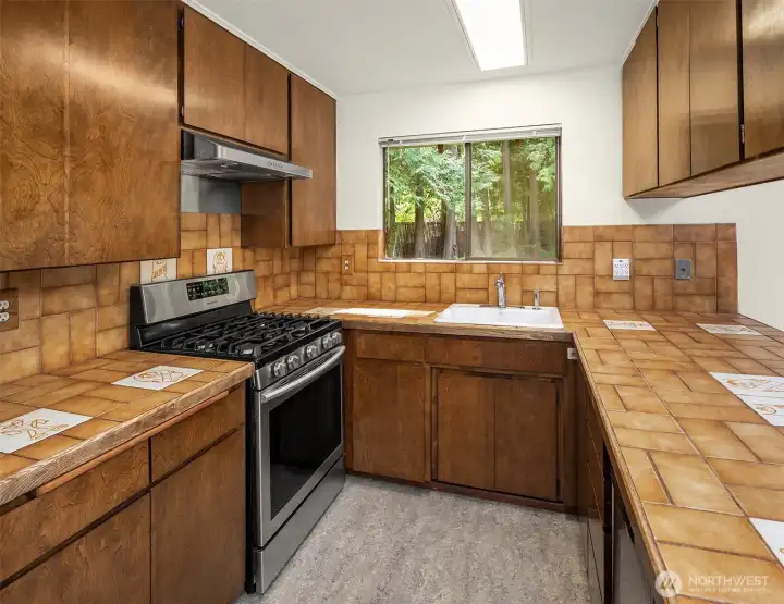 Kitchen with updated appliances; Fisher Paykel refrigerator and 5-burner Samsumg gas stove. Convenient kitchen counter for casual dining or chatting with the chef.