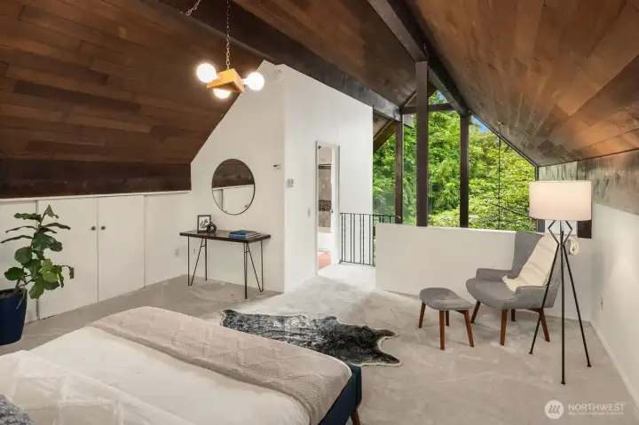 Large loft primary bedroom with everchanging views through A-frame window.