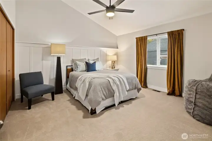 The secondary bedroom is light and inviting, featuring vaulted ceilings, beautiful wainscoting, and an airy sense of comfort.