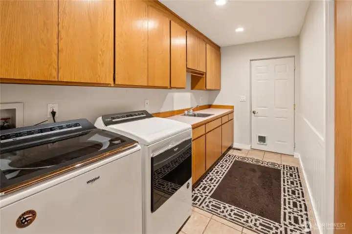 Spacious laundry room featuring ample storage, plenty of folding space, and a convenient sink.