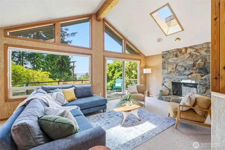 The living room with wall of windows to take in view of bay, slider to outdoor living and wood burning fireplace. The living room with wall of windows to take in view of bay, slider to outdoor living and wood burning fireplace.