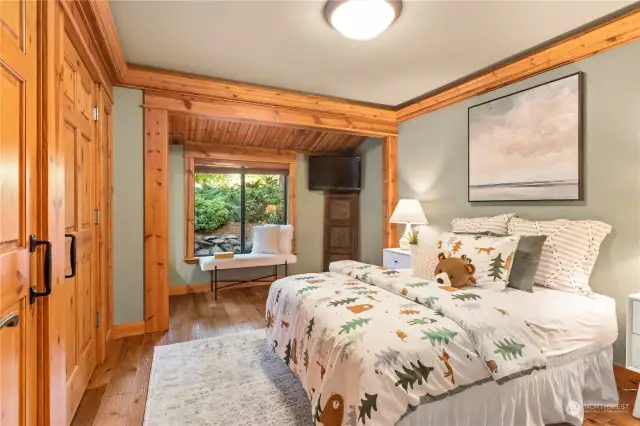 The third main level, spacious bedroom includes led crown molding lighting to accent the custom millwork, a comfortable sitting area, and large windows opening to the relaxing sound of the waterfall just outside.
